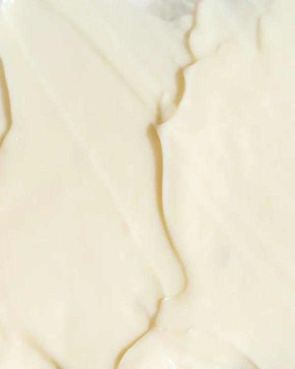 This image shows a close-up of a creamy, smooth texture with white and beige colors, possibly a dairy product like yogurt or cream.