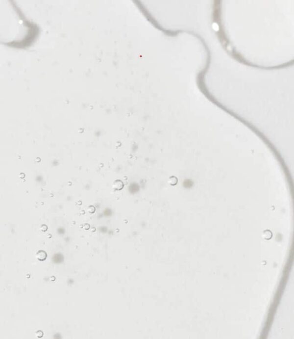 This image shows a close-up of a white liquid with various-sized bubbles and thin, meandering lines, possibly a spilled dairy product or a cleansing substance.