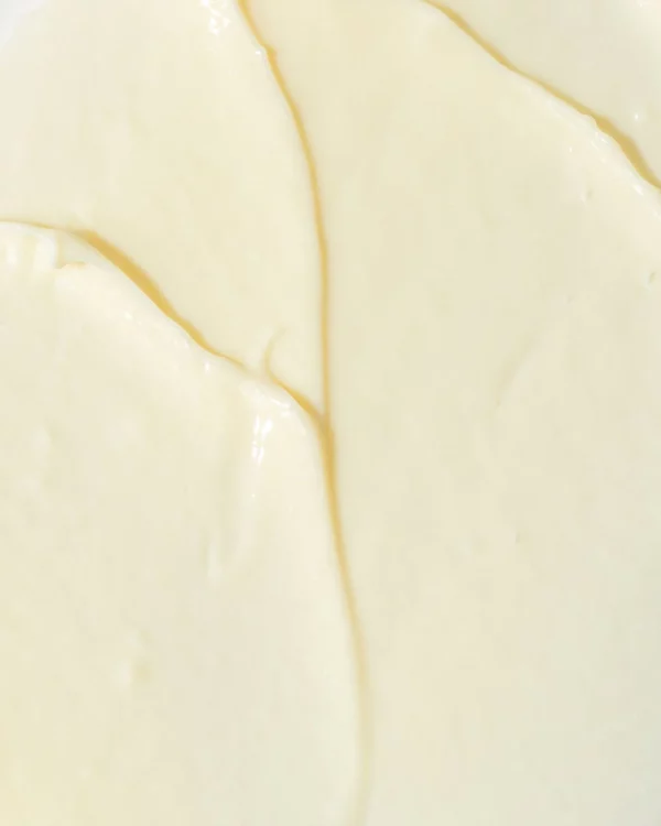 Close-up of creamy, smooth substance with soft folds and subtle yellowish tint, possibly a dairy product like cream cheese or yogurt.