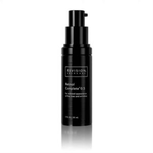 An isolated black skincare bottle with a pump dispenser; labeled "Revision Skincare Retinol Complete 0.5" for reducing fine lines and wrinkles.