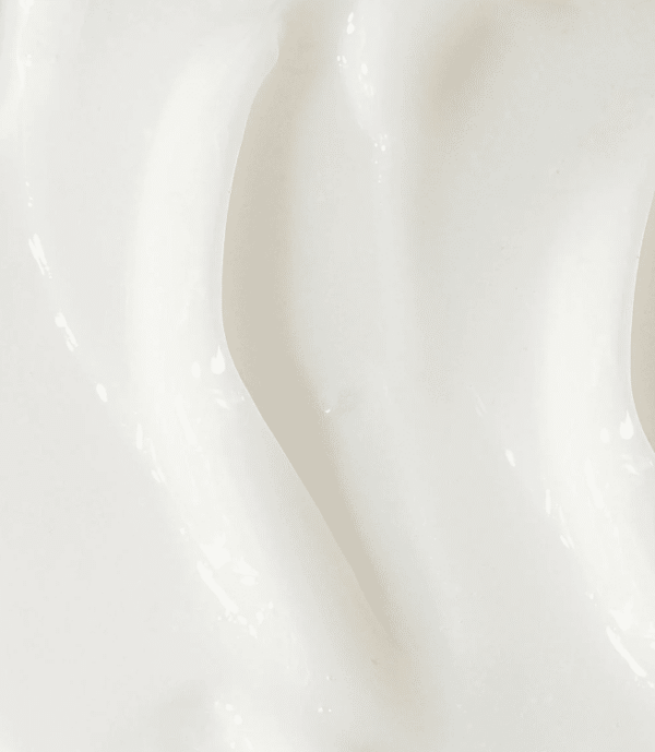 This image depicts a close-up of a white creamy substance, possibly cosmetic cream or yogurt, with smooth texture and subtle light reflections.