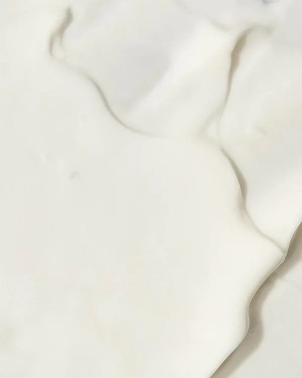 The image displays a creamy, white textured surface with soft curves and gentle folds, creating an abstract and smooth visual. It appears velvety and soft.