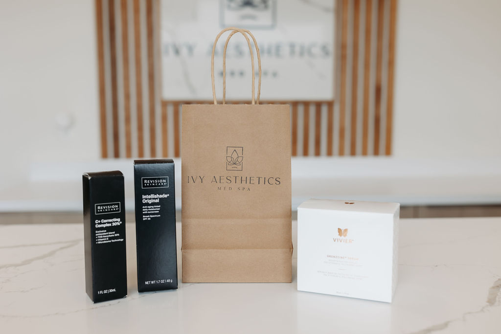 Aesthetic skincare products and a branded shopping bag are displayed on a marble surface in a modern med spa setting.