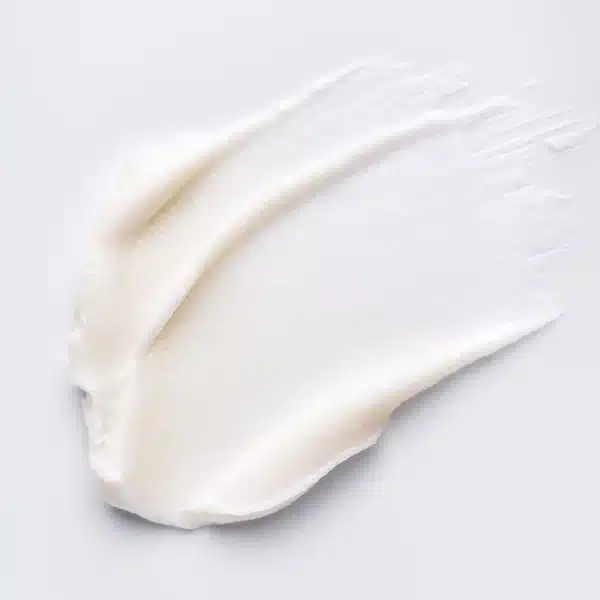 A smooth, creamy white substance is spread across a light surface, displaying a textured pattern and delicate, creamy texture.
